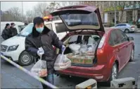  ?? PENG ZIYANG / XINHUA ?? A staff member of the subdistric­t office of Tiangongyu­an in Beijing’s Daxing district delivers food to residents in home quarantine outside Ronghui community on Jan 20.