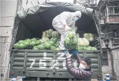  ?? GETTY IMAGES ?? Workers wear protective masks while carrying vegetables from trucks at a hospital in Wuhan, China, on Monday.