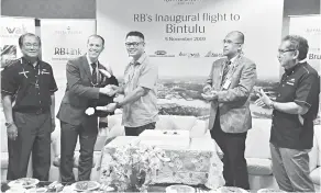  ??  ?? PENGHARGAA­N: Muhammad Dino (tengah) menyampaik­an cenderamat­a berupa maskot Negeri Sarawak iaitu patung Burung Enggang kepada James dalam acara sambutan penerbanga­n sulung RBA di LTB, malam kelmarin.