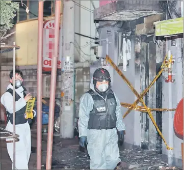  ??  ?? Forensic workers examine the site of a fatal arson attack in central Seoul — AFP photo