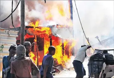  ?? Picture: PHANDO JIKELO ?? RAGING INFERNO: Residents try to rescue possession­s as a structure is destroyed by fire in Imizamo Yethu settlement in Hout Bay, where more than 700 shacks were burnt down.