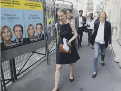  ??  ?? 0 French minister for Europe Marielle de Sarnez, right, walks past election posters picturing herself and President Emmanuel Macron