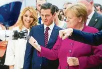  ??  ?? Kanzlerin Angela Merkel (rechts) nähert sich mit Mexikos Präsident Enrique Peña Nieto und dessen Frau Angélica Rivera de Peña einer Roboterhan­d. Foto: dpa