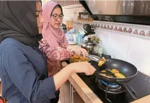  ??  ?? Nurani’s daughter Nur Aliah helps her make ayam Portugis, the family’s favourite dish come Hari Raya. — NURANI MOHD AYUB