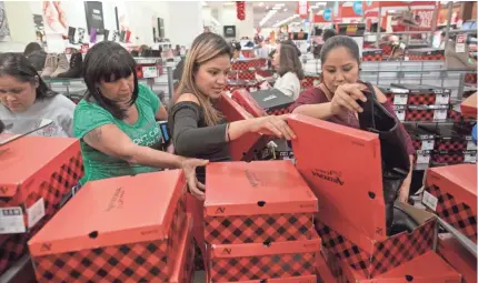  ??  ?? Shoppers search through boxes of boots at J.C. Penney in Corpus Christi, Texas, after the department store opened its doors at 2 p.m. on Thanksgivi­ng Day. COURTNEY SACCO/CORPUS CHRISTI CALLER-TIMES