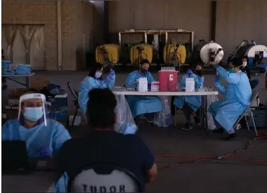  ?? (AP/Jae C. Hong) ?? Medical workers prepare the Pfizer-BioNTech covid-19 vaccine for farmworker­s Thursday at Tudor Ranch in Mecca, Calif. State health officials cleared the use of a batch of Moderna vaccine Thursday after a pause because of allergic reactions at one site.