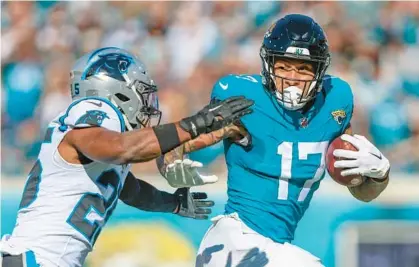  ?? GARY MCCULLOUGH/AP ?? Jags tight end Evan Engram escapes the grasp of Panthers safety Xavier Woods during Sunday’s game.