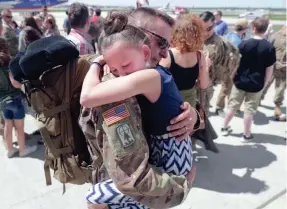  ??  ?? Capt. Michael Lindow hugs his 10-year-old daughter, Amalia, after arriving at the 128th Air Refueling Wing in Milwaukee on Thursday. Lindow’s wife, Erin, was there to greet him, too.