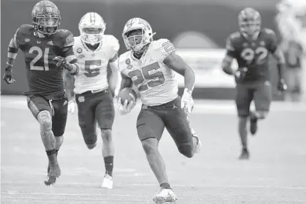  ?? MICHAEL LAUGHLIN | SUN SENTINEL ?? North Carolina running back Javonte Williams runs ahead of the Miami defense during the first half Saturday.