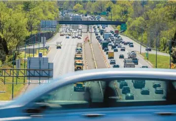  ?? KARL MERTON FERRON/STAFF ?? Seen from the Interstate 70/I-695 interchang­e Tuesday, a car passes above some of the 350 constructi­on vehicles calling attention to employees who were killed in work zone crashes.