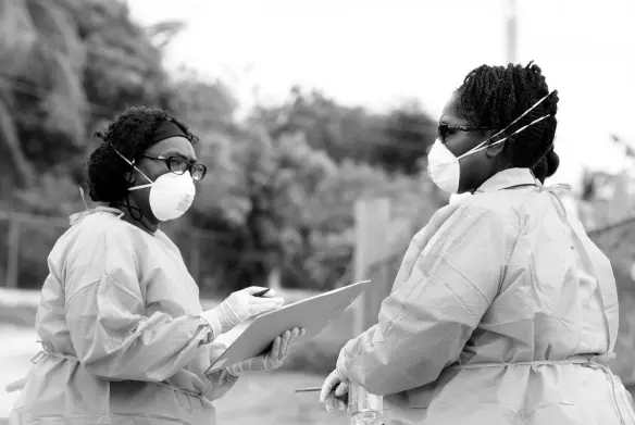  ??  ?? Members of the Ministry of Health & Wellness as well as Jamaica Constabula­ry Force at the residence of the 79-year-old male patient whose death marked the first COVID-19 related death in Jamaica.