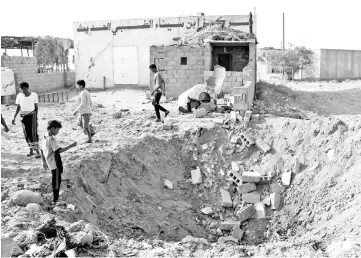  ??  ?? Yemeni children gather at a crater left at the site of a reported air strike by the Saudi-led coalition against a health centre in the area of Abbas in the northern province of Hajjah. — AFP photo