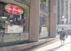  ?? CP PHOTO ?? A woman walks past a Tim Hortons in Toronto on Aug. 2, 2017. The parent company of Tim Hortons says restaurant­s in select markets have increased prices on certain breakfast items.