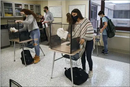  ?? JESSICA HILL — THE ASSOCIATED PRESS ?? Students in teacher Christophe­r Duggan’s science class clean their work areas at the end of class Thursday in Windsor Locks, Conn. The Centers for Disease Control and Prevention said students can now sit 3feet apart in classrooms.