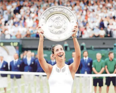  ?? FOTO: REUTERS ?? ►► Muguruza, levantando la bandeja que la acredita como ganadora de Wimbledon.