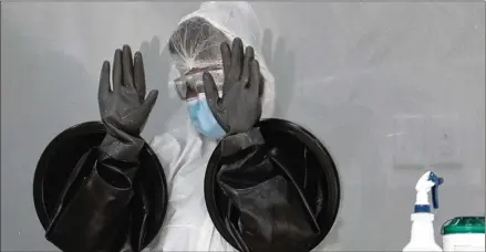  ?? LYNNE SLADKY / ASSOCIATED PRESS ?? A health care worker air dries her gloves after sanitizing her equipment while working at a walk-up testing site in Miami Beach, Fla. The testing truck is operated by Aardvark Mobile Health, which has partnered with the Florida Division of Emergency Management. People getting tested are separated from nurses via a glass pane.