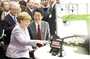  ??  ?? Abe and German Chancellor Angela Merkel looking at a sushi robot at the Hitachi booth during a media tour of the world’s biggest computer and software fair, CeBit, in Hanover, Germany. — Reuters photo