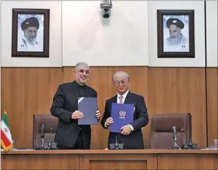  ?? PHOTO BY XINHUA ?? Ali Akbar Salehi (left), head of Atomic Energy Organizati­on of Iran, shows an agreement with Yukiya Amano, chief of the Internatio­nal Atomic Energy Agency, at a news conference in Teheran on Monday.
