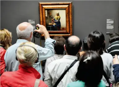  ?? ADAM MCDOWELL ?? Crowds jostle for a look at Vermeer’s The Milkmaid at the Rijksmuseu­m, which reopened in April after being closed for a decade for a €375-million renovation.