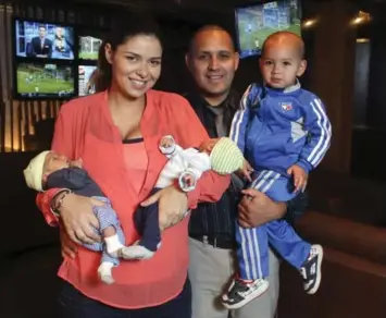  ?? ANDREW FRANCIS WALLACE/TORONTO STAR ?? Carlos Gavilanes, owner of Shoeless Joe’s, holds his 2-year-old son Santiago, while his wife, Stephanie, holds 2-week-old twin boys Salvador and Reyes. They are debating which form of daycare they are going to use.