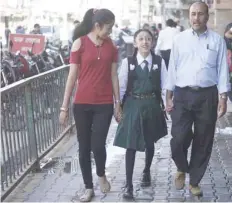  ?? — AFP ?? Matina Shakya walks to school with her father Pratap Man Shakya and sister Mijala Shakya for the first time in nearly a decade in Kathmandu on Monday.