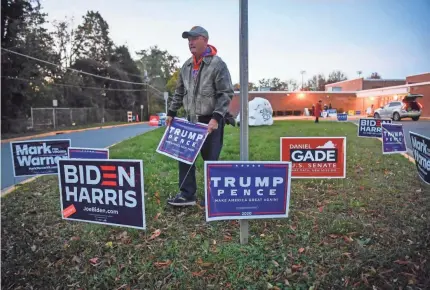  ?? JACK GRUBER/USA TODAY ?? Trump supporter and volunteer Rob Gardenier places signs outside a Virginia polling place Nov. 3.