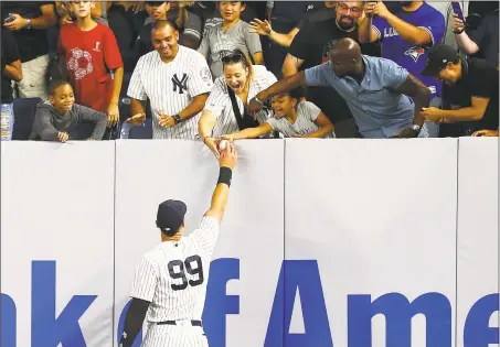  ?? Mike Stobe / Getty Images ?? Aaron Judge gives a fan a baseball while warming up in the eighth inning for the first time after being activated from the disable list.