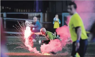  ?? JUSTIN TANG THE CANADIAN PRESS ?? A security guard picks up a flare that was thrown onto the field during Wednesday night’s game in Ottawa.