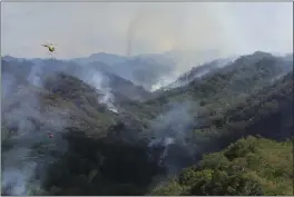  ?? DAN DENNISON — HAWAII DEPARTMENT OF LAND AND NATURAL RESOURCES VIA AP ?? An Army helicopter carries water to douse a wildfire burning east of Mililani, Hawaii, on Thursday. The blaze is taking a toll on native rainforest and fragile species.