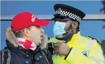  ?? PHOTO: REUTERS ?? Resisting lockdown . . . A police officer wearing a protective mask speaks to a demonstrat­or during a protest against the coronaviru­s lockdown in Britain, at Clapham Common yesterday.