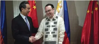  ?? —AFP ?? MANILA: China’s Foreign Minister Wang Yi (L) shakes hand with Philippine Foreign Affairs scretary Alan Peter Cayetano after signing the Guestbook.