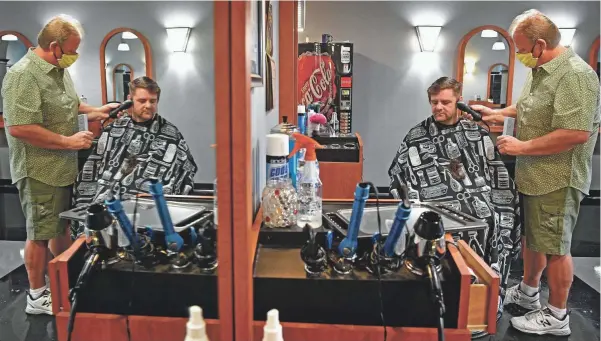  ?? LARRY MCCORMACK / THE TENNESSEAN ?? After being away from his shop for over six weeks Greg Smith is glad to be back cutting hair in Lebanon on Wednesday. His first customer of the day was Brandon Schramm, who said he had waited way too long for a haircut.