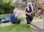  ??  ?? Firefighte­rs who quickly extinguish­ed a house fire on West Fourth Street Wednesday found some relief from the heat with bottled water and towels wet from a neighbor’s hose.