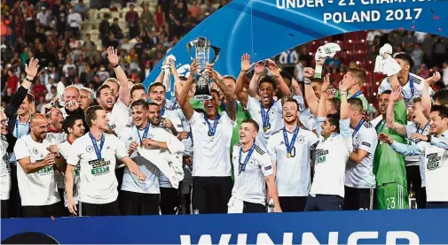  ??  ?? German players celebrate with the trophy after winning the UEFA Under-21 European Championsh­ip in Krakow, Poland, on Friday. Germany beat Spain 1- 0. Below: Mitchell Weiser (centre) heads the ball home for Germany. — AFP / AP