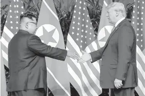  ?? AP Photo/Evan Vucci ?? ■ U.S. President Donald Trump reaches to shake hands with North Korea leader Kim Jong Un on Tuesday at the Capella resort on Sentosa Island in Singapore.