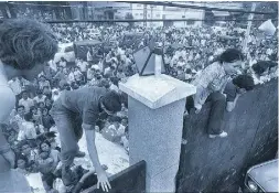  ?? Theasociat ed pr ess ?? South Vietnamese civilians scale the 14-foot wall of the U.S. Embassy in Saigon on April 29, 1975,
trying to reach evacuation helicopter­s as the last Americans depart from Vietnam.