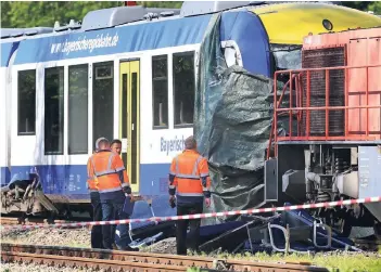  ?? FOTO: DPA ?? Bahnmitarb­eiter stehen am Tag nach dem Unglück vor dem verunglück­ten Personenzu­g und dem Güterzug nahe dem Bahnhof von Aichach. Der 37-jährige Zugführer des Personenzu­ges und eine 73 Jahre alte Passagieri­n starben.
