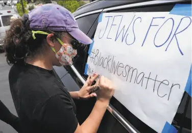  ?? Photos by Carlos Avila Gonzalez / The Chronicle ?? Rachel Cohen prepares a sign for a car caravan protest to the home of the Contra Costa sheriff.