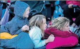  ?? Kent Nishimura Los Angeles Times ?? LUCAS WRIGHT, 6, left, Payson Wright, 9, and Ephram Wright, 11, get comfortabl­e while they wait for f loats to make their way down Colorado Boulevard.