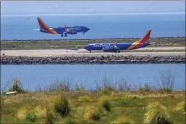 ?? RAY CHAVEZ — STAFF PHOTOGRAPH­ER ?? A Southwest airplane arrives as another gets ready to depart from the Oakland Internatio­nal Airport, seen from San Leandro on Thursday.