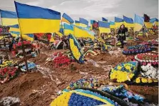  ?? Vadim Ghirda/Associated Press ?? A woman searches for the grave of her husband, a Ukrainian serviceman killed in the Bakhmut area, on Friday.