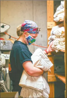  ??  ?? Zoey Marciniak, camp photograph­er, sorts T-shirts at Camp Wapsie.