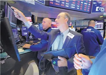  ?? RICHARD DREW/ASSOCIATED PRESS ?? Trader Joe Dente, front, and specialist Mark Fitzgerald work on the floor of the New York Stock Exchange on Tuesday. Stocks soared on Wall Street led by gains in technology and health care companies.