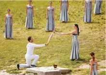  ?? AP-Yonhap ?? Actress Mary Mina, right, playing high priestess, gives the flame to the first torchbeare­r, Greek Olympic gold medalist Stefanos Douskos, during the official ceremony of the flame lighting for the Paris Olympics at the Ancient Olympia site in Greece, Tuesday.