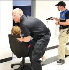  ?? ?? Pea Ridge Fire Lt. Chris Hunt transports a patient through the hallway guarded by a police officer during the active shooter drill.