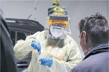  ?? REUTERS ?? Certified nursing assistant Shameka Johnson, wearing NFL Green Bay Packers apparel, processes a nasal swab at a drive-through testing site outside the Southside Health Centre in Milwaukee, Wisconsin.