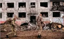  ?? Lynsey Addario/New York Times ?? Ukrainian soldiers walk by a destroyed building on Sunday in Druzhkivka, Ukraine, as fighting in Donetsk continues.