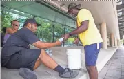  ?? TOM TINGLE/THE REPUBLIC ?? Salvation Army volunteer Jowan Thornton hands water to Alex Jimenez near a Phoenix park on a recent hot day.