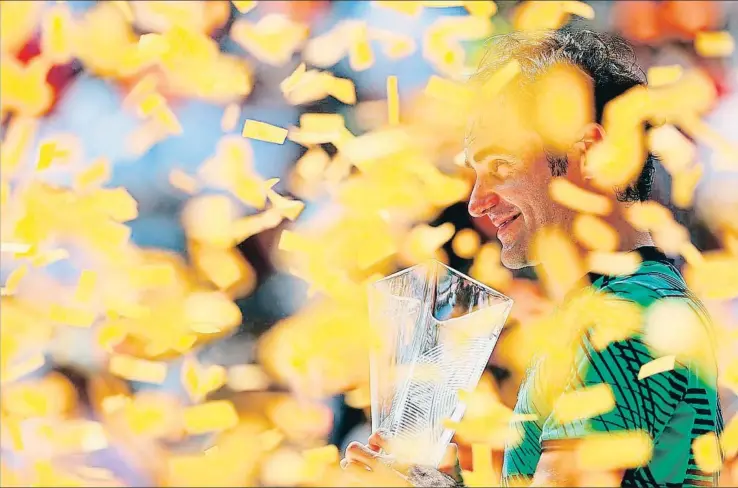  ?? AL BELLO / AFP ?? Federer, que está en una forma espectacul­ar, sonríe con el trofeo en las manos y rodeado por los pedacitos de papel clásicos en las ceremonias de proclamaci­ón de campeones