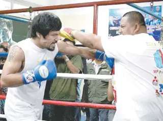  ?? AFP PHOTO ?? Manny Pacquiao ( left) works the mitts with trainer and friend Buboy Fernandez.